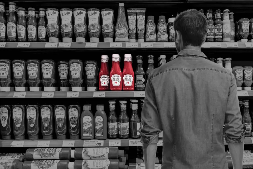 Man in front of the sauce aisle, with ketchup bottles in focus