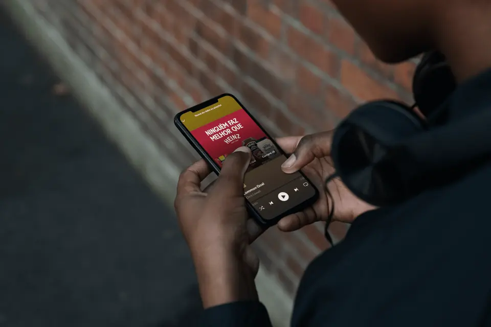Person with headphones listening to music on a phone, with a ketchup audio ad