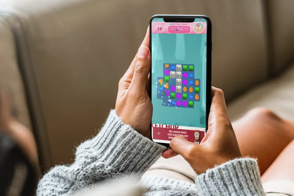 Person on the couch playing a mobile game, with a ketchup ad on screen
